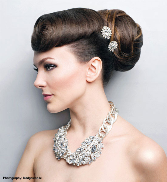 A formally dressed woman wearing an elegant hairpiece and a stylish necklace.