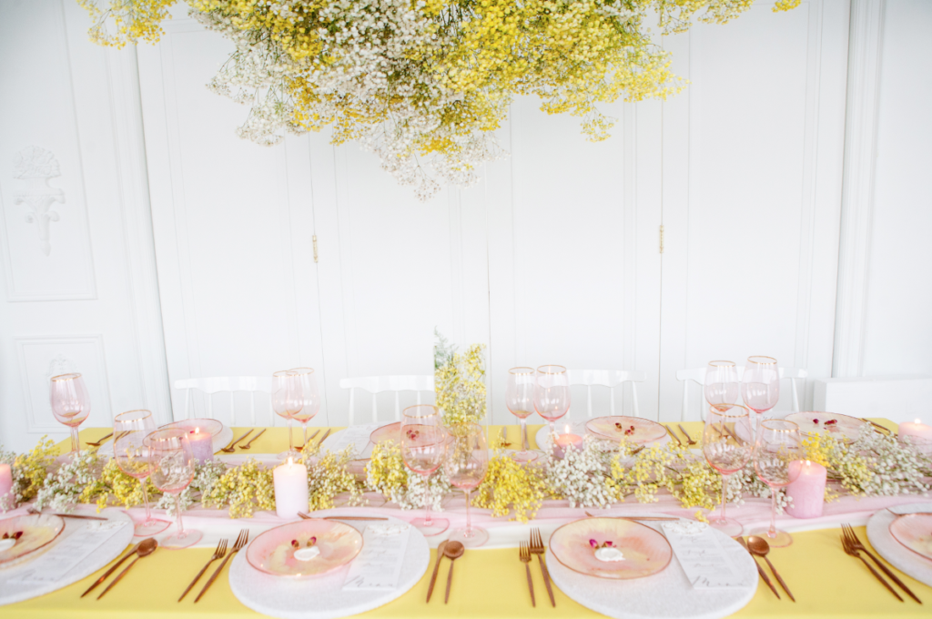 beautiful wedding table in butter yellow linens and flowers suspended from the ceiling planned perfectly using wedding decor checklist