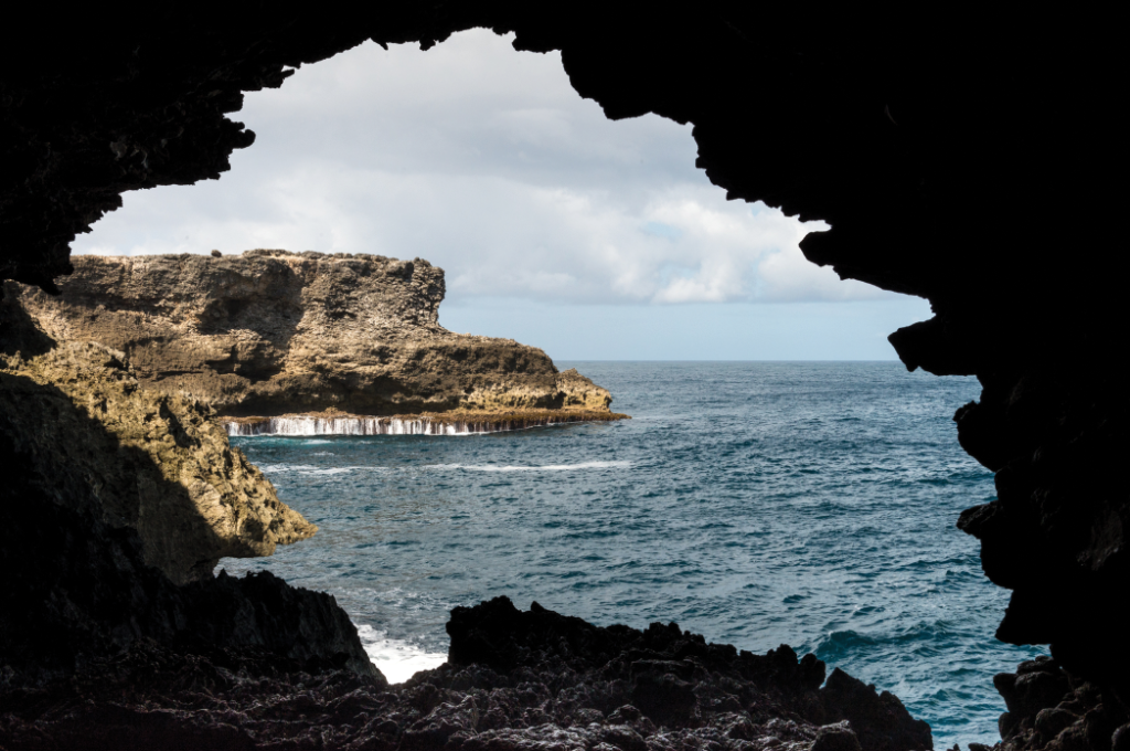 A serene ocean vista seen through the entrance of a cavernous cave, showcasing the beauty of nature's juxtaposition.