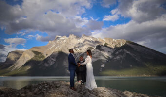 most incredible destination wedding locations bride and groom typing the knot outdoors with Banff mountains as backdrop