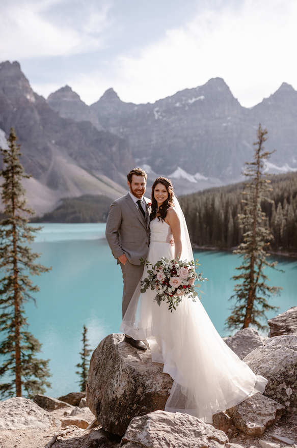 bride and groom pose for portrait with Lake Louise in the backgound