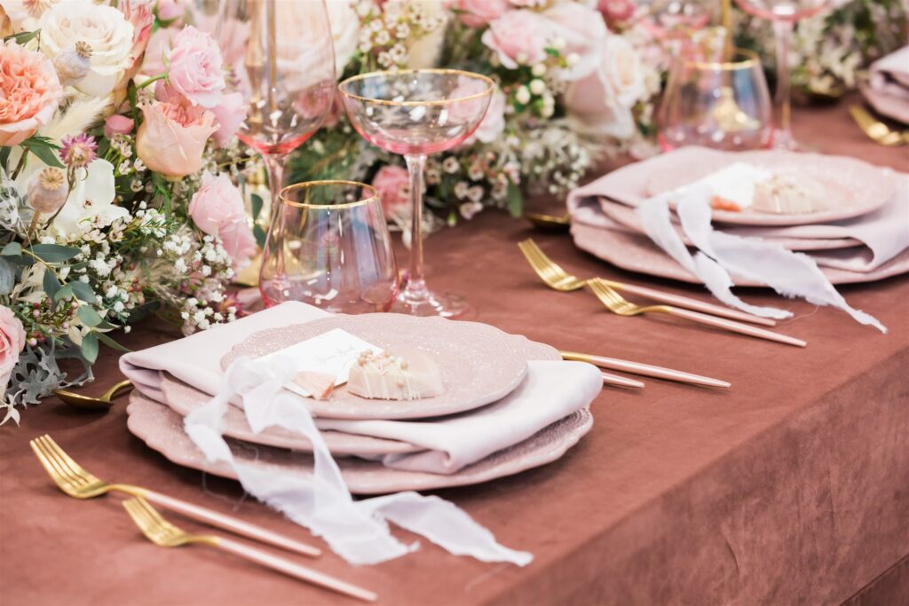 A formal table setting with elegant pink and gold plates and matching napkins.