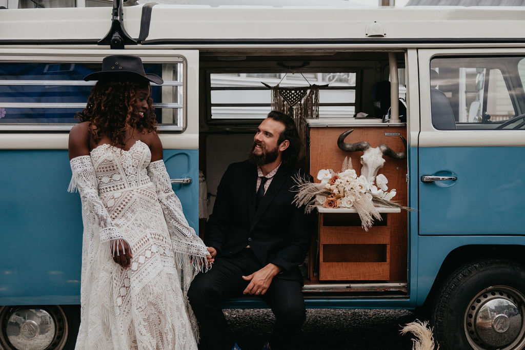 bride and groom pose in front of vintage VW van during western wedding - one of the hotest wedding decor trends in 2025