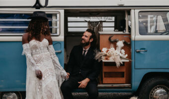 bride and groom pose in front of vintage VW van during western wedding - one of the hotest wedding decor trends in 2025