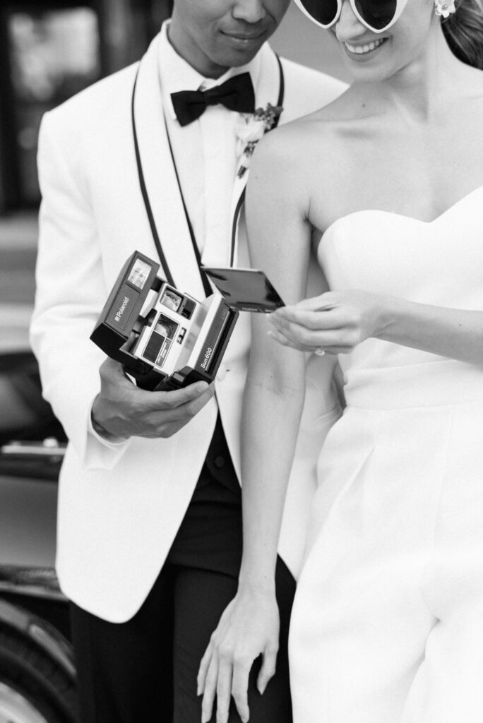 retro wedding theme groom wearing white jacket polaroid camera