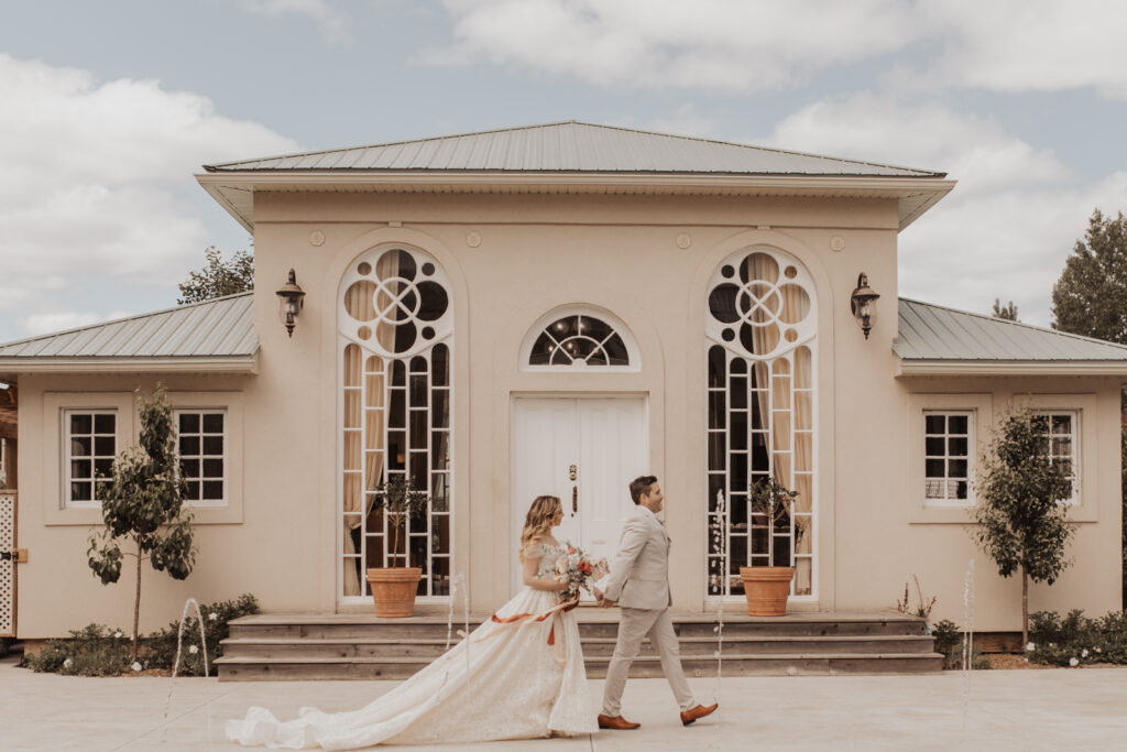 bride and groom portrait walking in front of Manoir Chamberland 