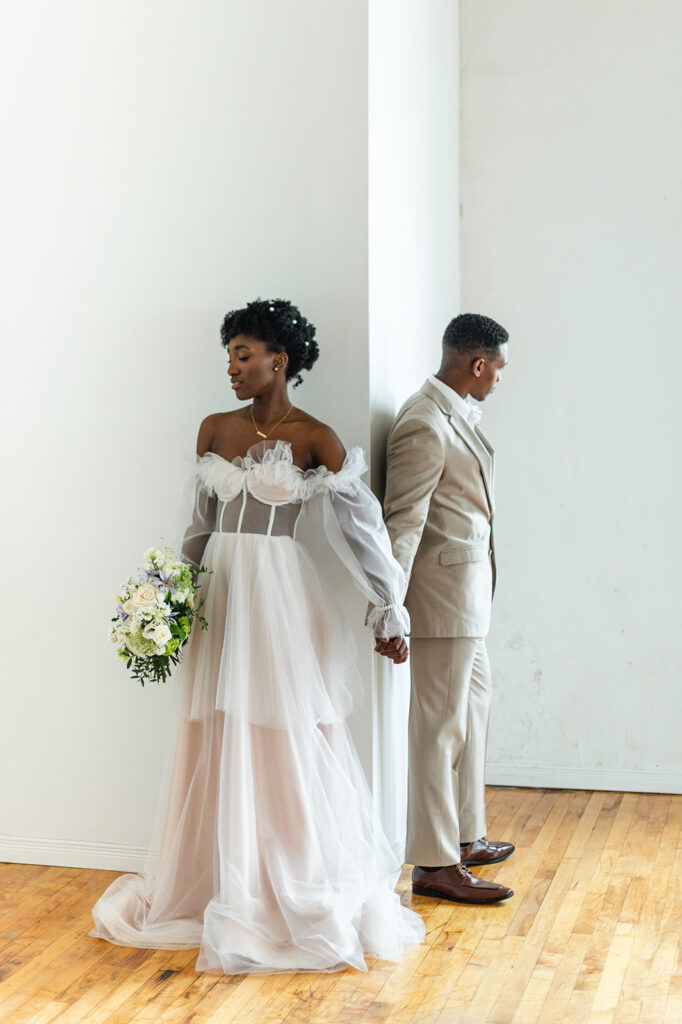 bride and groom pose for first look during wedding day timeline