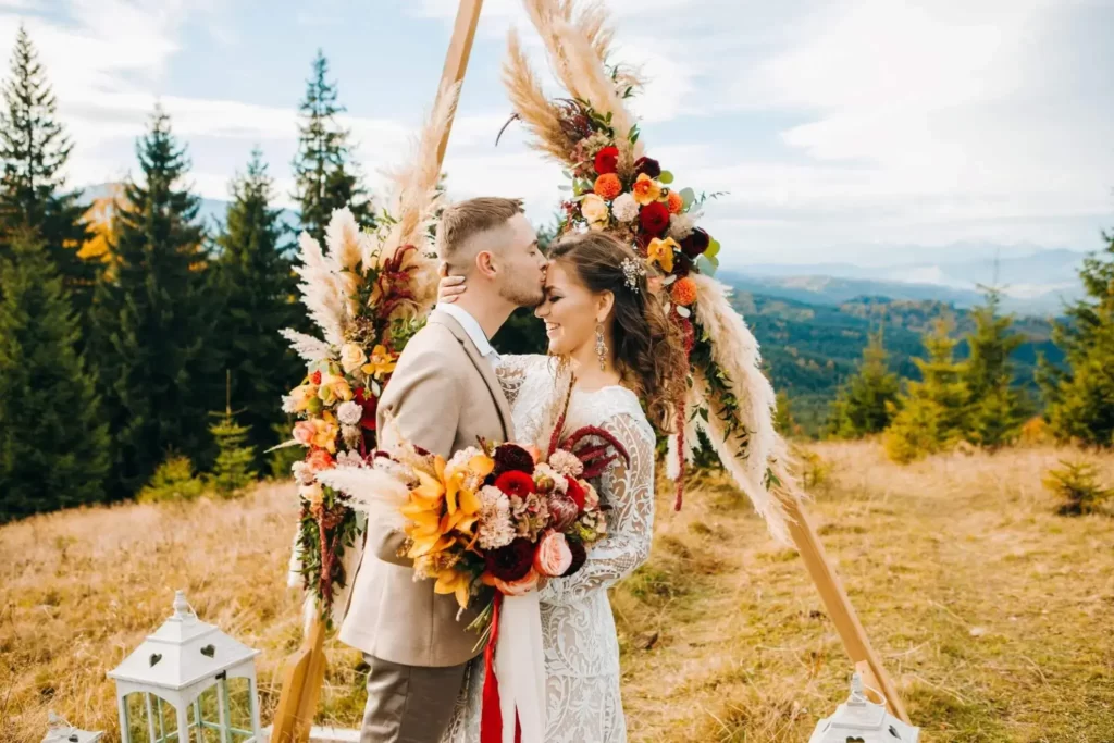 groom-kisses-bride-on-forehead-at-beautiful-boho-mountain-wedding-with-geometric-arch-
