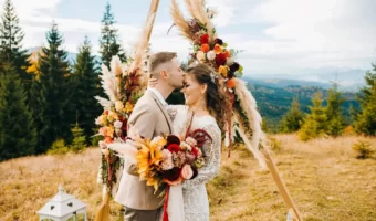 groom-kisses-bride-on-forehead-at-beautiful-boho-mountain-wedding-with-geometric-arch-