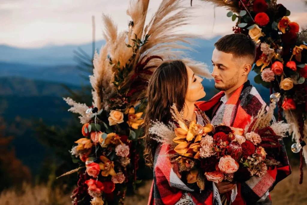 nighttime portrait of boho bride and groom in front of mountaintop altar wrapped in boho blanket