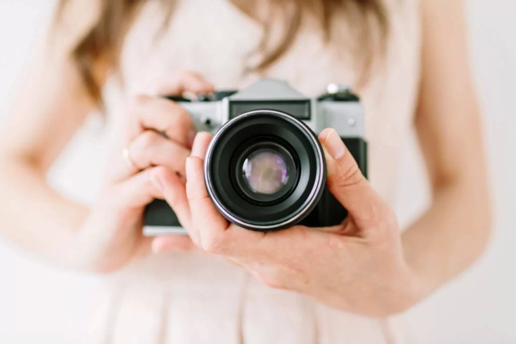 wedding photographer in blush dress holding camera