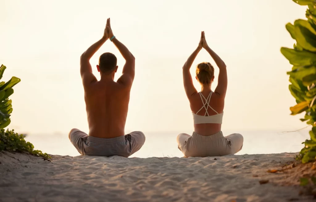 bride and groom meditating next to lake for couples wellness