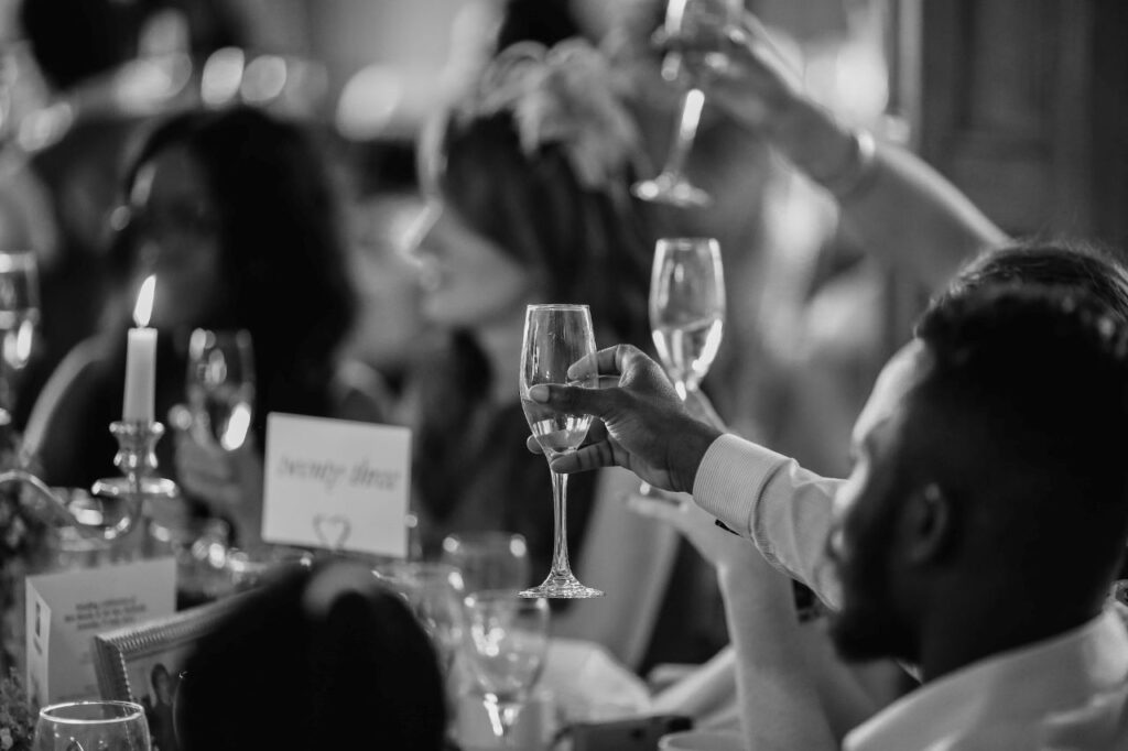 guests toasting champagne to wedding speech black and white photo