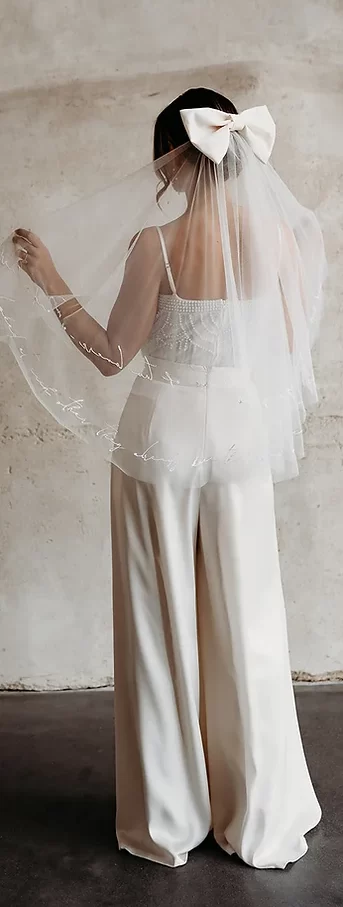 Bride wearing sheer veil with embroidered message along edge with a large bow at the top