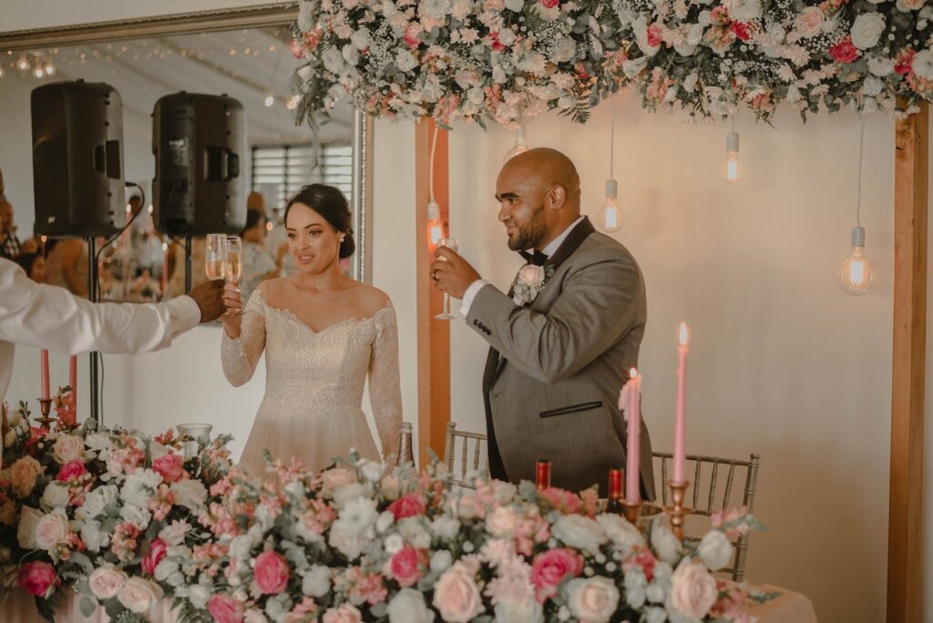 bride and groom standing listening to wedding speech and toasting champagne