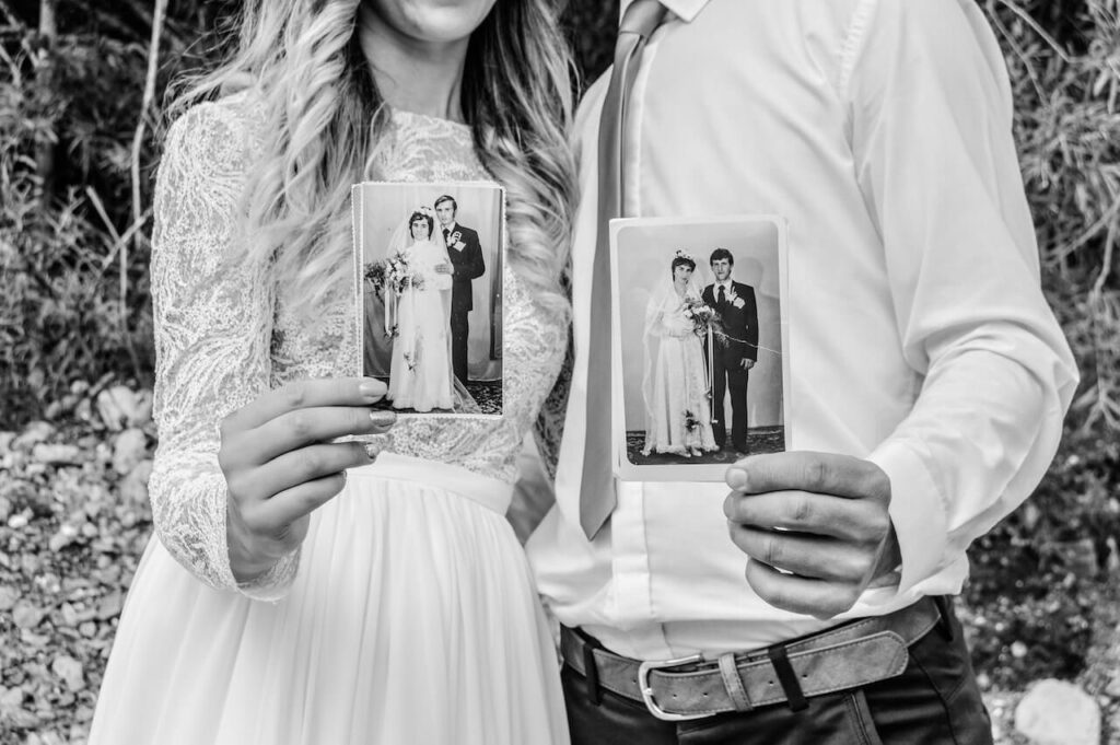 bride and groom holding photos of ancestors for black and white wedding photography