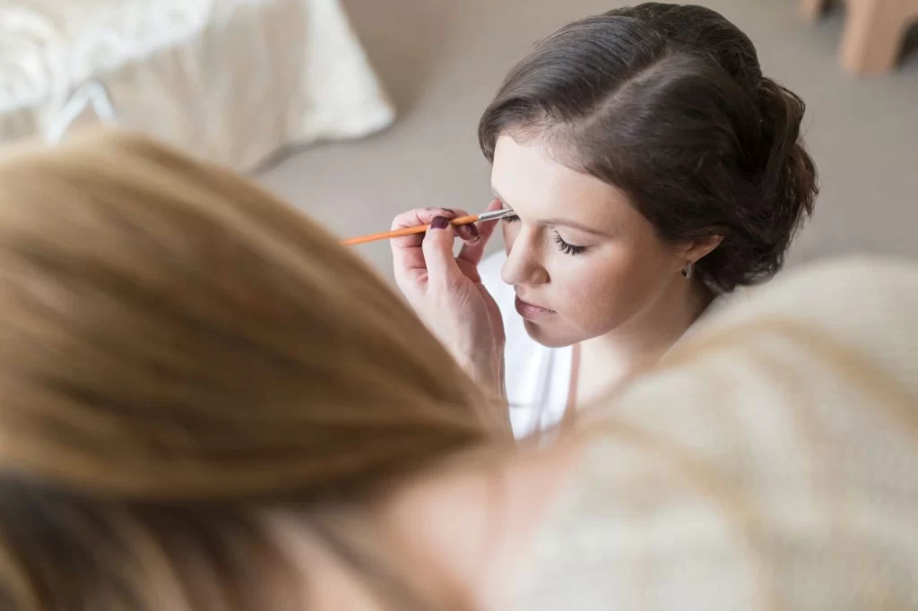 makeup artist putting on eyelash extensions on bride