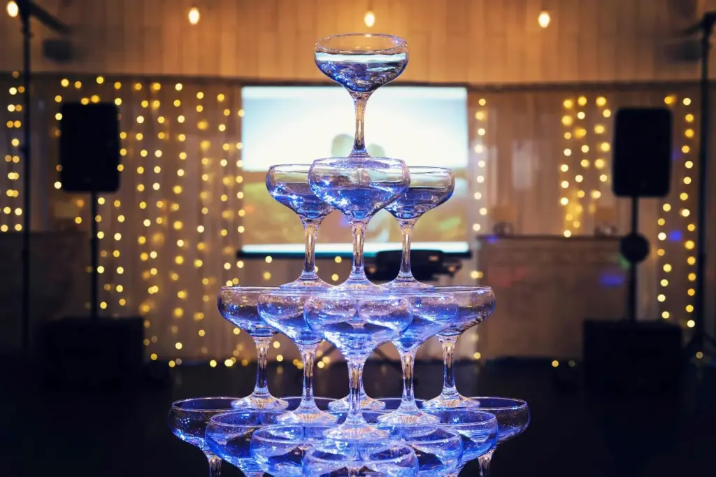 A champagne wedding tower built in the centre of decorated wedding room with projector screen in the back