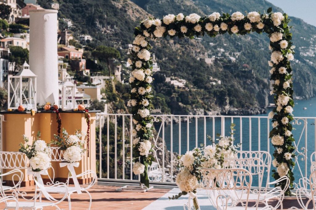 Amalfi Coast seaside wedding ceremony with beautiful arch with white flowers and greenery