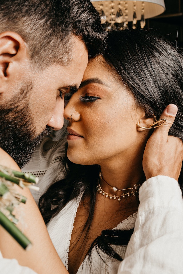 bride wearing choker necklace embraces groom for romantic portrait wearing a boho v-neck wedding dresses