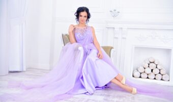 beautiful bride sitting in white room wearing purple wedding dress