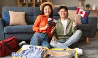 Asian couple holding Canada flag while honeymoon packing in living room