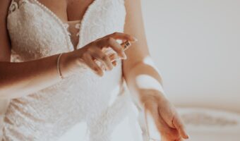 bride wearing v neck wedding dress spritzing wedding perfume on wrist