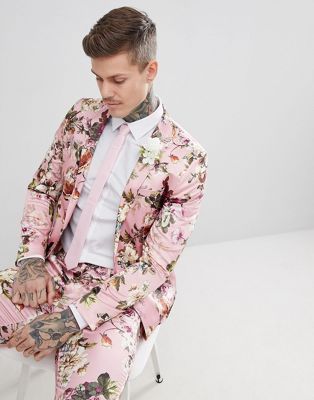 A tattooed groom exudes style in a pink floral wedding suit