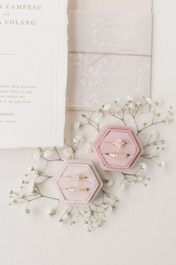 A formal wedding invitation featuring elegant calligraphy, accompanied by a delicate pink ring box and a charming bouquet of baby's breath.