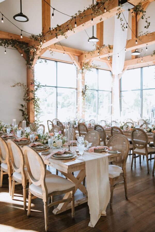 Charming wedding reception in a rustic barn adorned with wooden beams and elegant white chairs