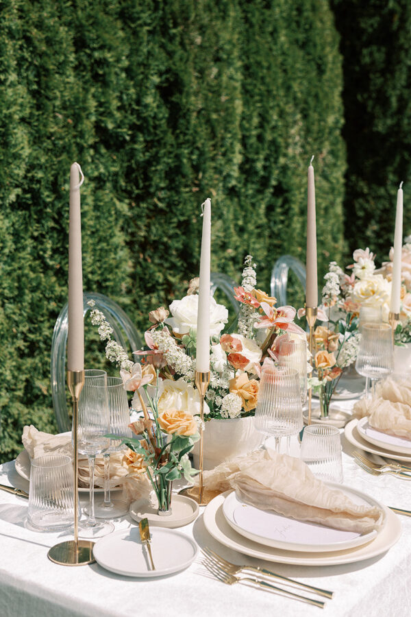 A beautifully arranged table in a garden setting, adorned with elegant place settings and centerpieces, ready for a wedding reception