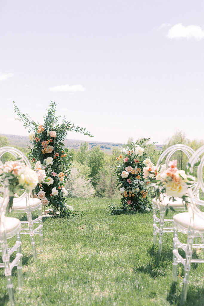 A beautiful outdoor wedding ceremony with rows of white chairs and vibrant flowers adorning the aisle.