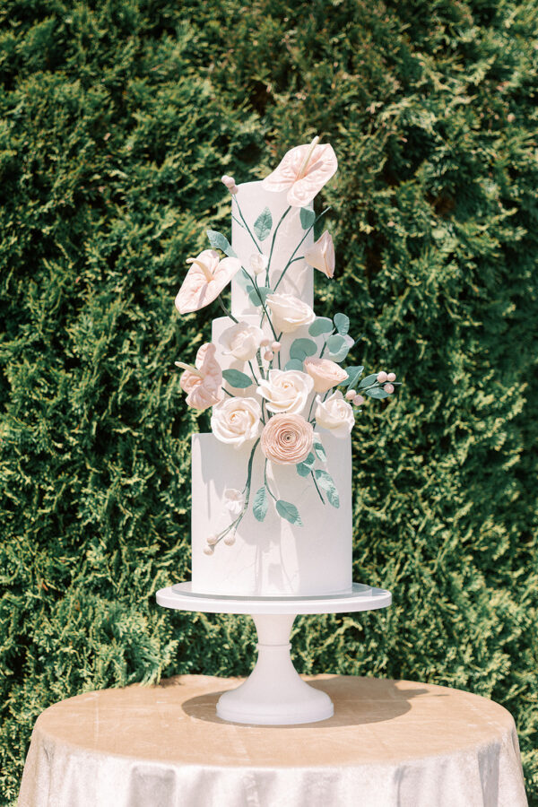 A formal white wedding cake adorned with delicate pink roses as a charming centerpiece.