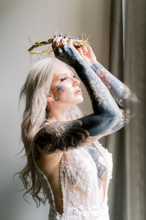 A regal woman adorned with tattoos and a crown atop her head exudes power and confidence.