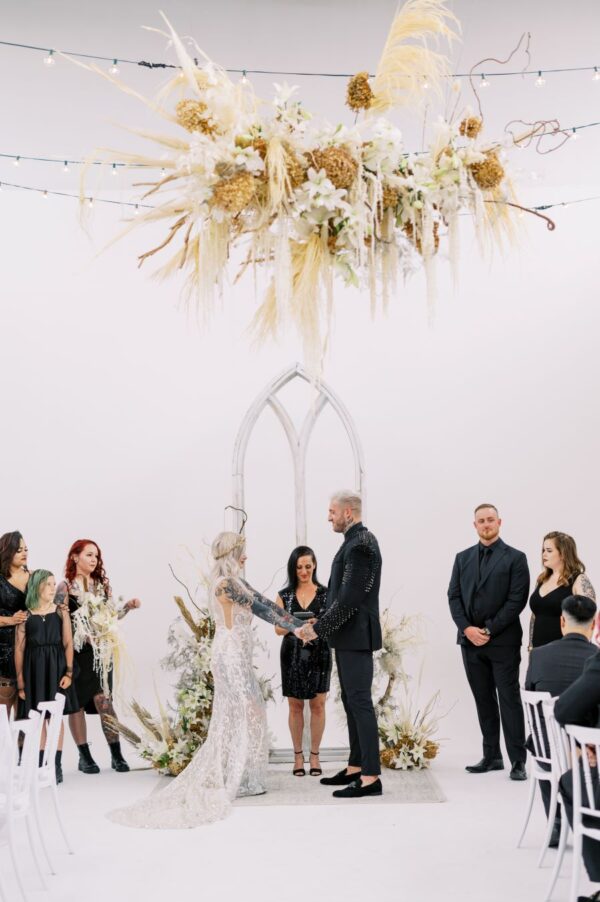 A formal wedding ceremony taking place in an elegant white room adorned with a magnificent chandelier.