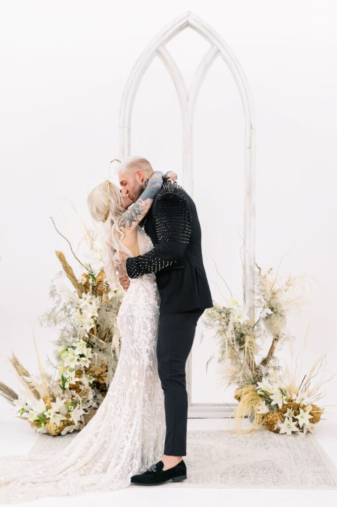 A serene chapel setting for a formal wedding ceremony, featuring Memphis Mori & Bradley kissing