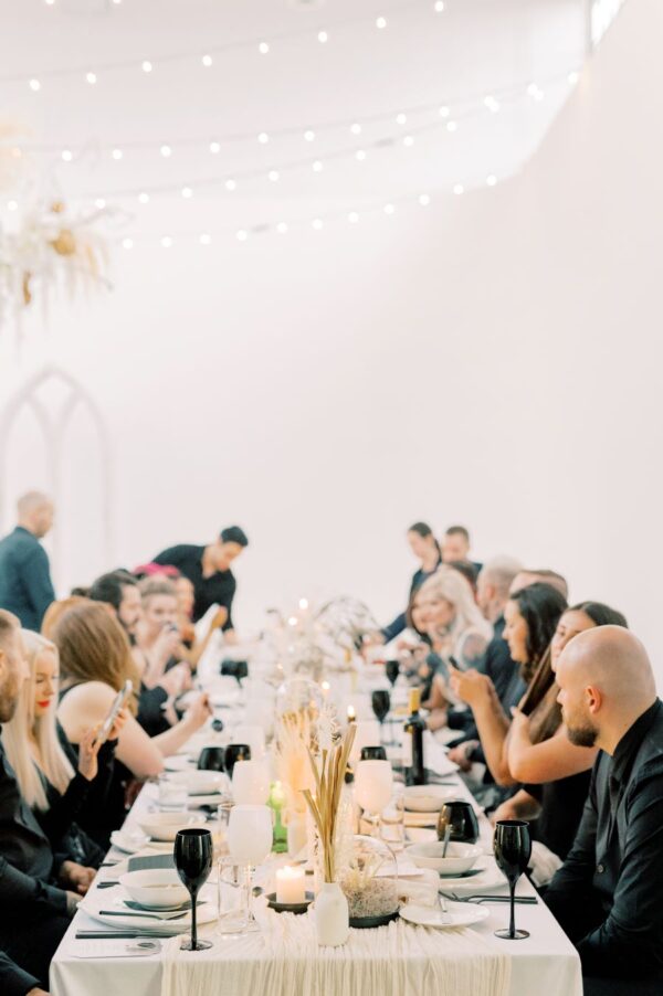 A formal wedding reception set in an elegant white room, featuring a long table adorned with exquisite decorations.