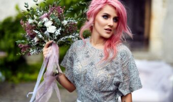 woman with pink wedding hairstyle poses while holding gorgeous bouquet