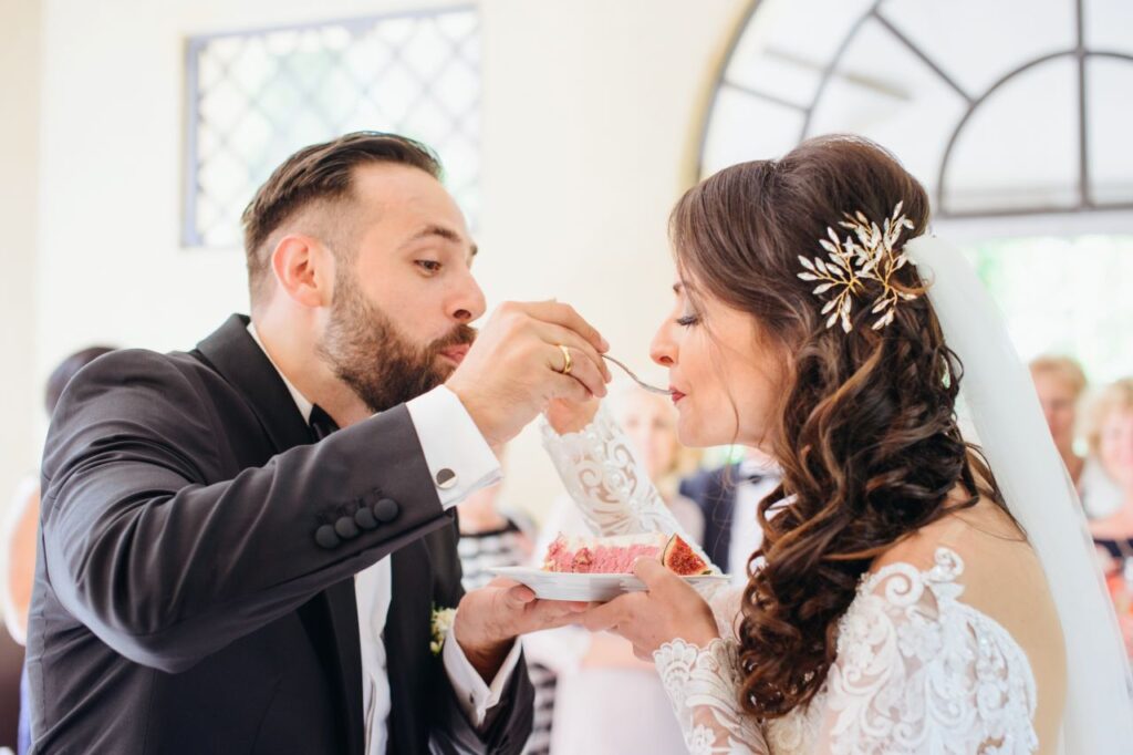 bride and groom eat wedding cake off one plate at reception - wedding cake tasting