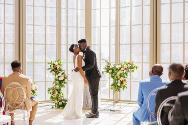 Newlyweds stand before guests in stunning ballroom.
