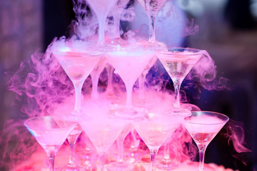 A stack of martini glasses filled with pink smoke, creating an alluring and vibrant ambiance.