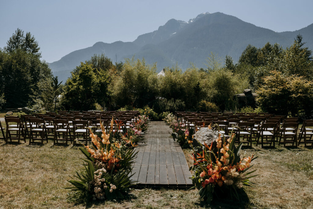 Outdoor wedding ceremony with chairs and flowers set against a stunning mountain backdrop.