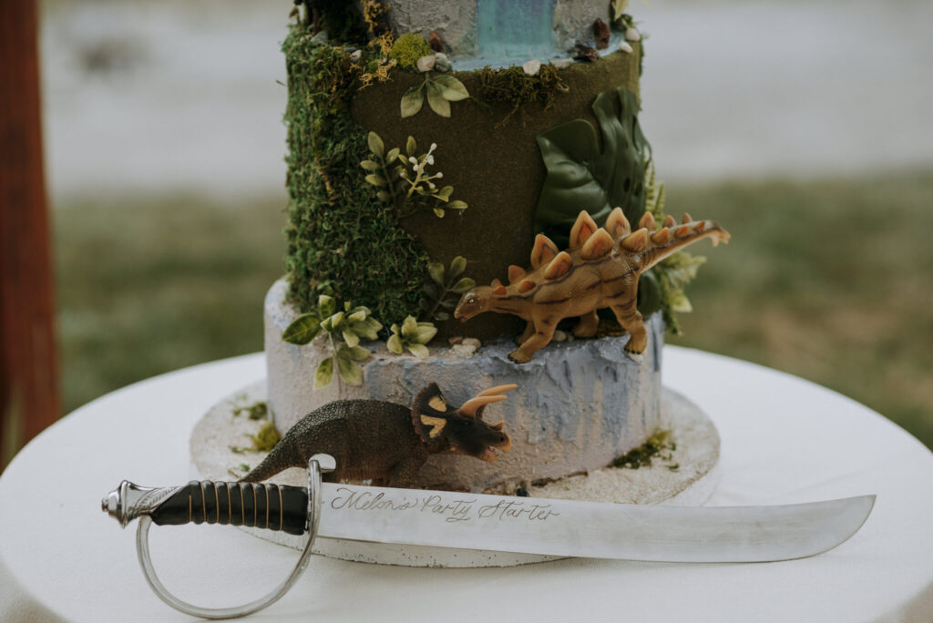Unique wedding cake featuring playful dinosaur figurines and a knife.