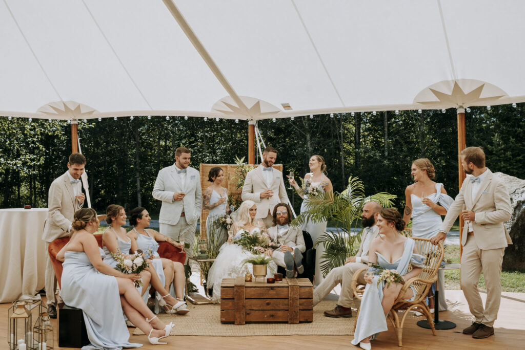 A wedding party celebrating inside a white tent, adorned with elegant decorations and filled with joyful guests.