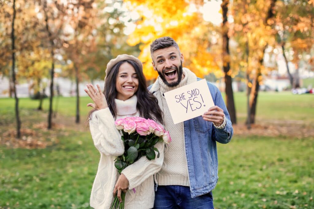 A joyful couple in the park, holding a sign that says 