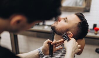 groom in barber's chair getting beard and sideburns trimmed