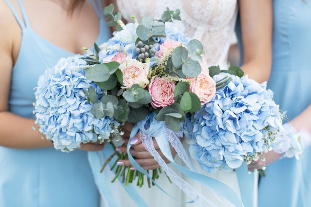 bridesmaids wearing blue dresses holding blue hydrangea bouquets a great wedding planning idea