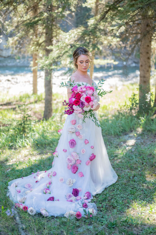 Beautiful bride holding large bridal bouquet filled with pink flowers in various shades for Barbie-styled wedding. Removable overlay skirt with handsewn pink flowers