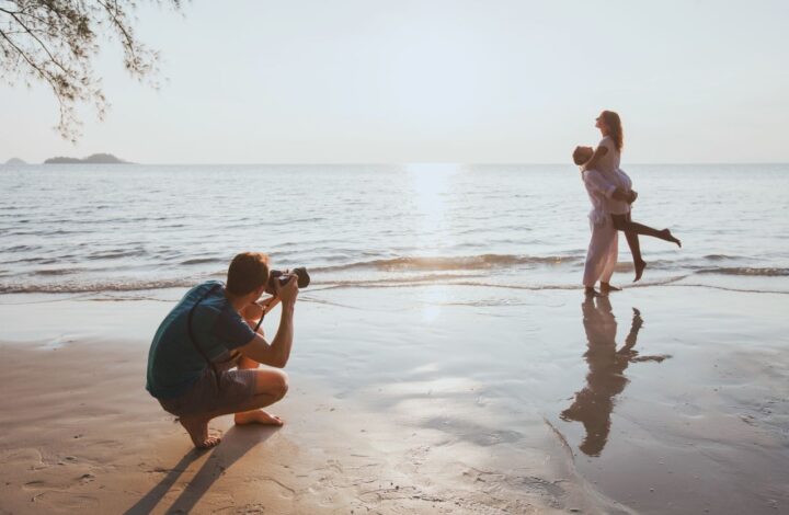 newlyweds pose on beach while photographer capture beautiful image during honeymoon photo shoots