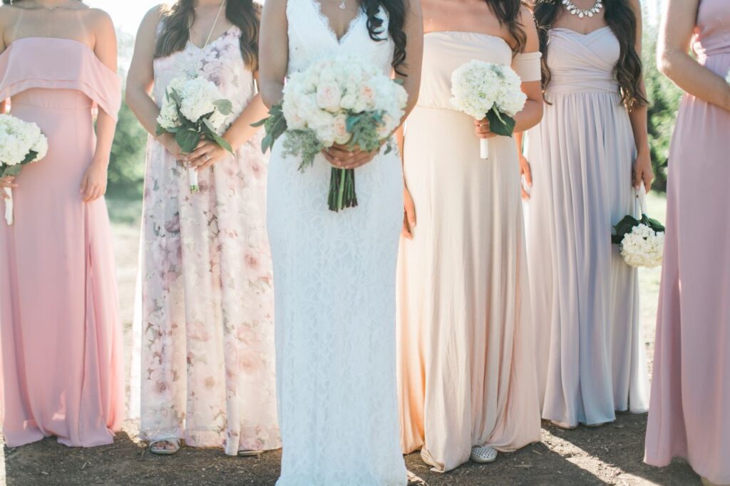 beautiful image of bride and her bridesmaids wearing mistmatched bridesmaid dresses in pastel colors and floral print holding bouquets